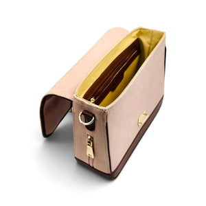 A blush pink denim shoulder bag with dark brown leather trim by needlesay, gold-tone hardware, and a bright yellow interior lining, shown open on a white background.