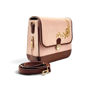 Needlesay structured rectangular shoulder bag in blush pink denim and dark brown genuine leather with gold floral embroidery on the front flap and gold-tone hardware, shown with a detachable brown shoulder strap on a white background. the collection name is botanica