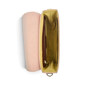 A blush pink denim and leather shoulder bag by needlsay is shown open, displaying its mustard yellow interior lining, zippered compartments, and a small gold-tone metal ring at the bottom.