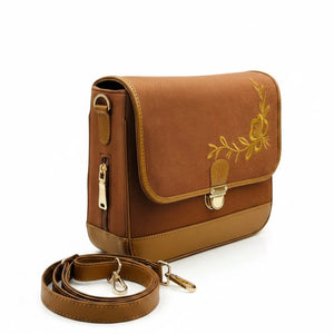 A brown denim crossbody bag of needlesay with a gold floral embroidery on the front flap, a gold-tone buckle, and a matching brown detachable shoulder strap, displayed on a clean white background.