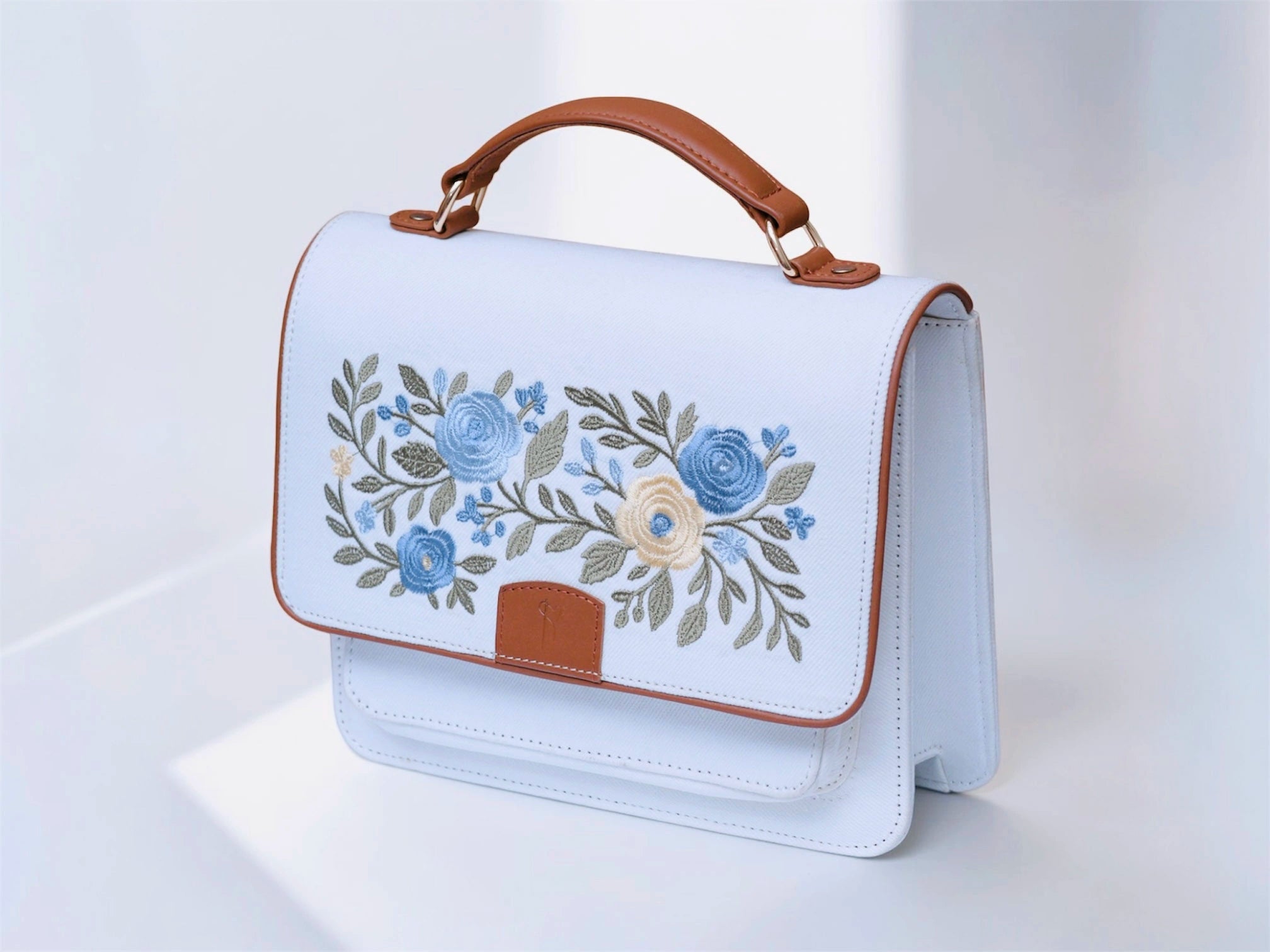 needlesay ivory White handbag with floral embroidery and brown handles on a white background