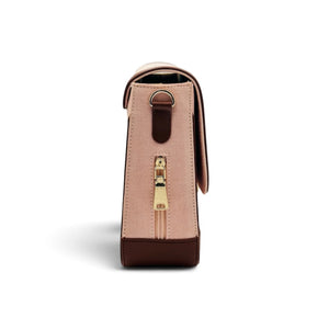 A structured handbag of needlesay called botanica blush shown from the back, featuring a light pink denim body with dark brown leather trim and a gold-tone zipper pull.