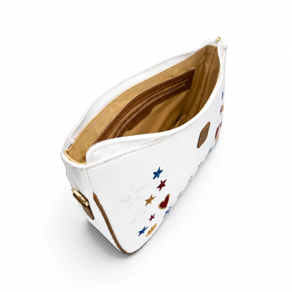 Angled view of the Needlesay white denim shoulder bag showing colorful embroidery, brown leather trim, gold-tone hardware, and tan interior lining with zip pocket.