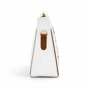 Side view of the Needlesay white denim shoulder bag showing brown leather edging, leather strap attachment, gold-tone D-ring, and structured design.